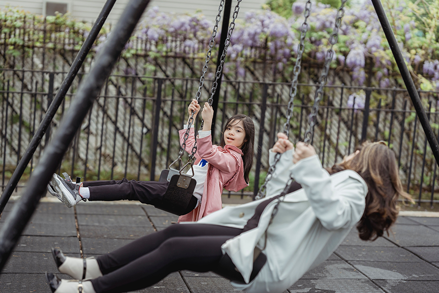 Children enjoying traditional belt swings on a commercial playground swing set in a community park.